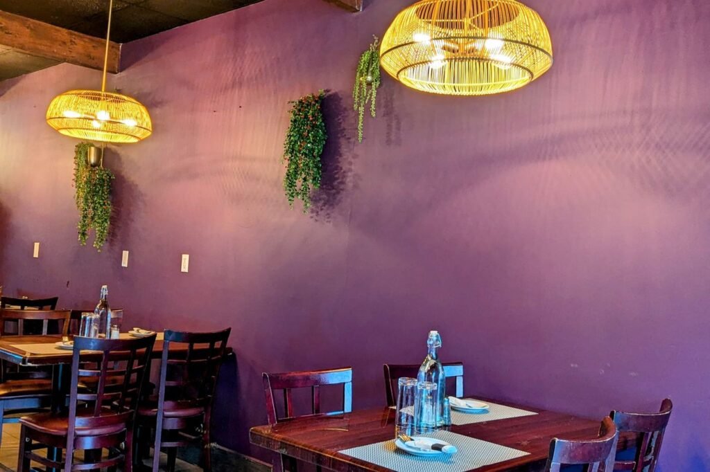 Tables against the plum-painted wall with trailing plants
