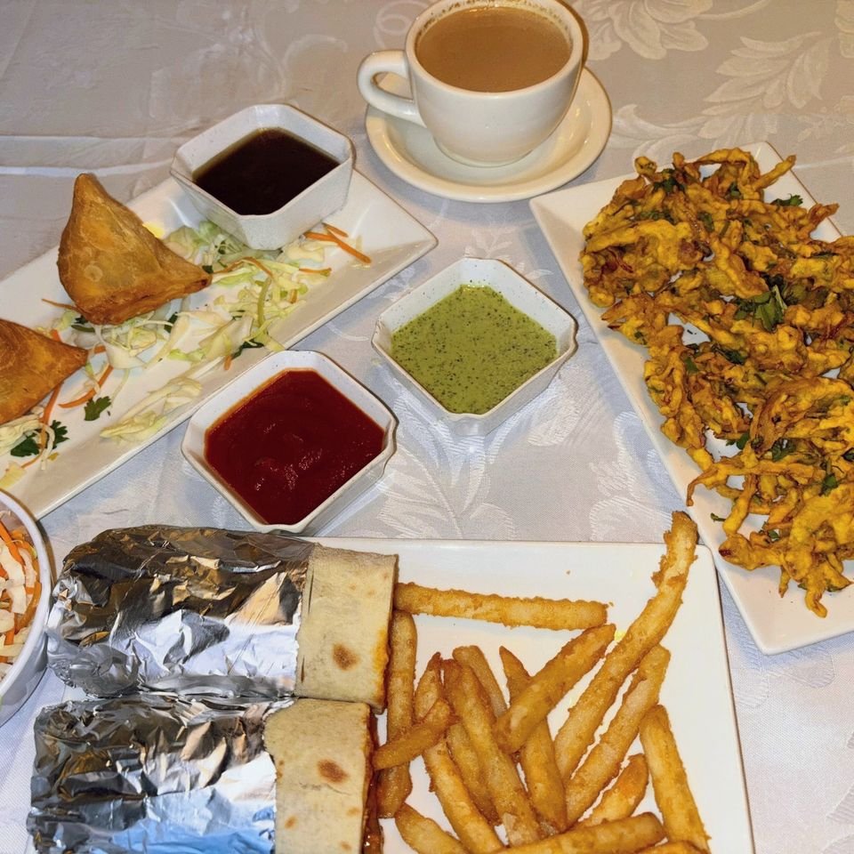 Samosa, onion pakora, a kathi roll with fries and a cup of masala chai